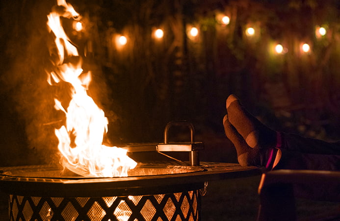 Person, with feet up, sits beside a fire pit