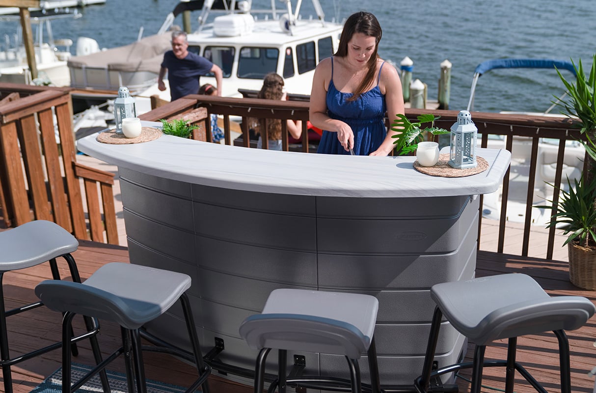 Woman preparing drinks at a Backyard Oasis Entertaining Bar on a seaside deck